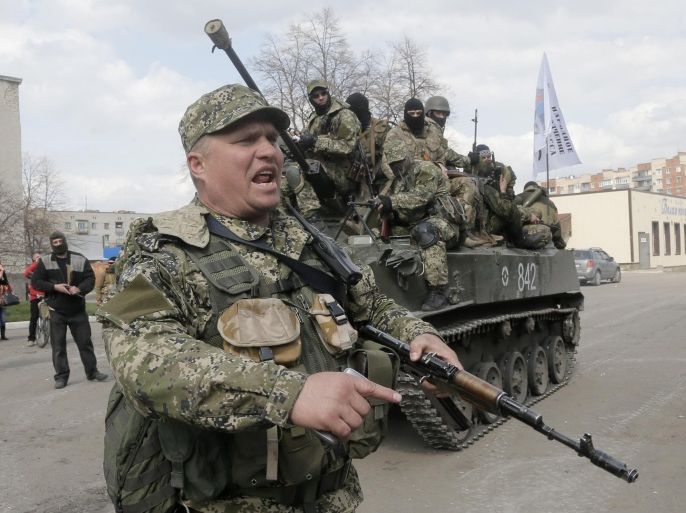 A pro-Russian gunman clears the way for a combat vehicle with gunmen on top in Slovyansk Wednesday, April 16, 2014. The troops on those vehicles wore green camouflage uniforms, had automatic weapons and grenade launchers and at least one had the St. George ribbon attached to his uniform, which has become a symbol of the pro-Russian insurgency in eastern Ukraine. (AP Photo/Efrem Lukatsky)