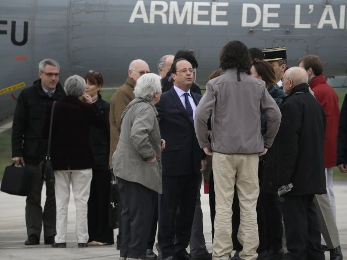 French President Francois Hollande (C) welcomes four French journalists, Edouard Elias, Didier Francois, Nicolas Henin and Pierre Torres, taken hostage in Syria last year and freed yesterday, and their families at the Villacoublay air base southwest of Paris on April 20, 2014. They had been captured in two separate incidents in June last year while covering the conflict in Syria. AFP PHOTO / KENZO TRIBOUILLARD