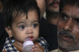An unidentified family member with a nine-month-old boy, leave after the boy's court appearance in Lahore, Pakistan, Saturday, April 12, 2014. A Pakistani lawyer said a judge has freed the boy accused of attempting to murder police in the eastern city of Lahore after police withdrew charges. (AP Photo/K.M. Chaudary)