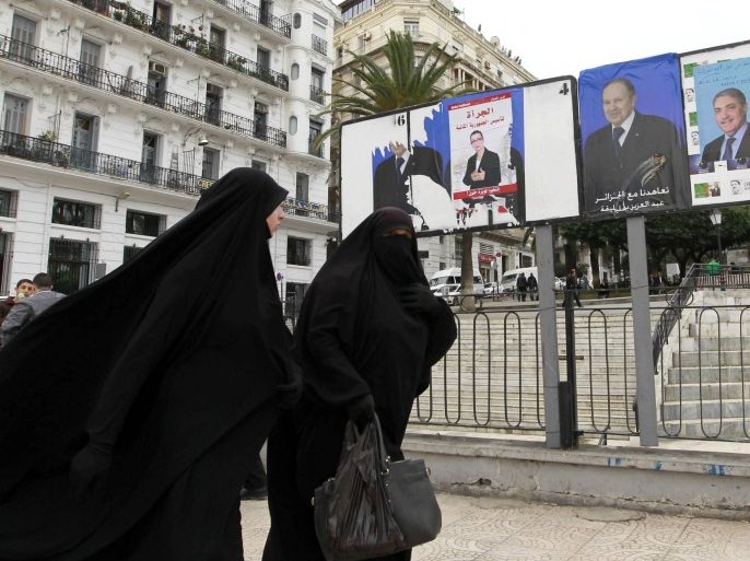Algerian women walk past electoral posters in Algiers, April 2, 2014. Campaigning began on March 23 for an Algerian presidential election widely seen as a one-horse race that will ensure President Abdelaziz Bouteflika's a fourth term. REUTERS/Louafi Larbi (ALGERIA - Tags: POLITICS SOCIETY ELECTIONS)