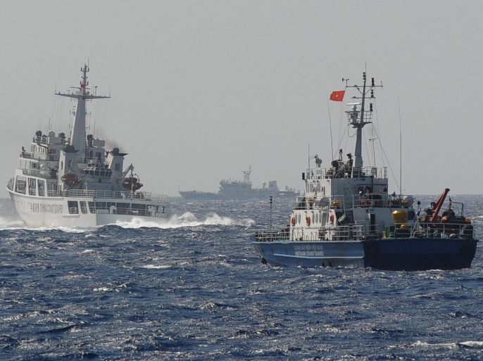 This picture taken on May 14, 2014 shows a Chinese coast guard vessel (L) followed by a Vietnamese coast guard ship (R) near the area of China's oil drilling rig in disputed waters in the South China Sea. Vietnam is experiencing its worst anti-China unrest in decades following Beijing's deployment of an oil rig to disputed waters, with at least one Chinese worker killed and more than 100 injured. AFP PHOTO / HOANG DINH NAM