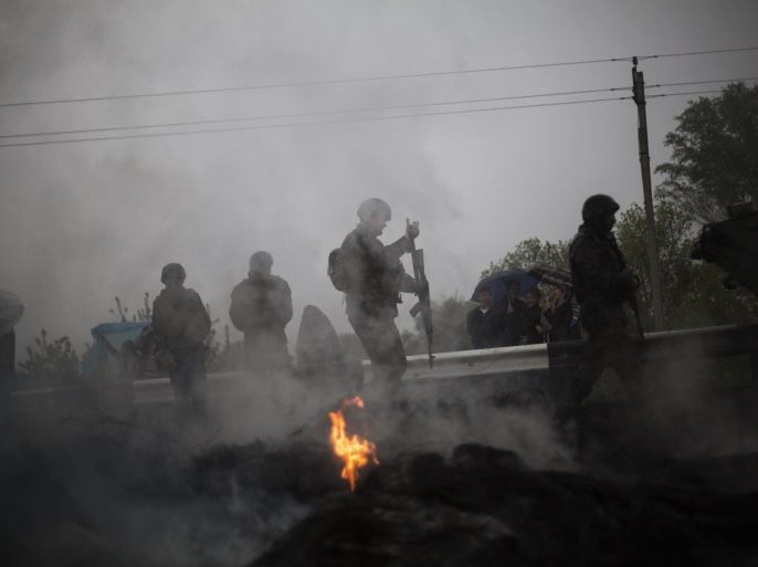 Ukrainian Army soldier walks behind a burnt barricade while Pro Russia civilians are blocking the road to Slaviansk in the village of Andreevka, 10 km south to Slaviansk ,Ukraine, Friday, May 2, 2014. Russia has massed tens of thousands of troops in areas near Ukraine’s border. Kiev officials claim Russia is preparing to invade and that it is fomenting the unrest in the east, where insurgents have seized government buildings in about a dozen cities in towns. Moscow denies the allegations, but Foreign Minister Sergey Lavrov has warned Russia would respond to attacks on Russian citizens or interests in the east. (AP Photo/Manu Brabo)