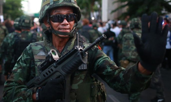 A Thai soldier gestures after being reinforced at the Victory Monument during an anti-coup demonstration in Bangkok, Thailand, Saturday, May 24, 2014. Thailand's coup leaders said Saturday that they would keep former Prime Minister Yingluck Shinawatra, Cabinet members and anti-government protest leaders detained for up to a week to give them "time to think" and to keep the country calm. They also summoned outspoken academics to report to the junta. (AP Photo/Wason Wanichakorn)