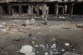 A soldier walks past damaged buildings following Tuesday's car bomb explosion in Jos, Nigeria, Thursday, May 22, 2014. Two car bombs exploded at a bustling bus terminal and a market in Nigeria's central city of Jos on Tuesday, killing over 100 people, wounding dozens and leaving bloodied bodies amid the flaming debris. There was no immediate claim of responsibility for the twin car bombs. (AP Photo/Sunday Alamba)