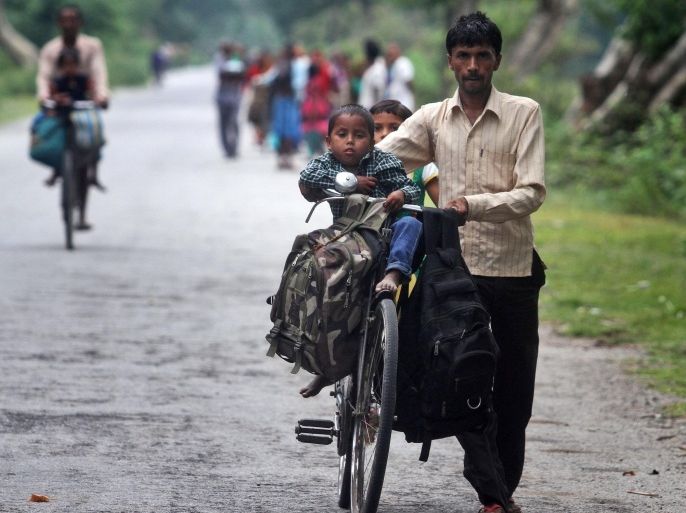 A villager pushes a bicycle carrying children and belongings, leaving their violence-affected village of Narayanguri, in the northeastern Indian state of Assam, Saturday, May 3 2014. Police in India arrested 22 people after separatist rebels went on a rampage, burning homes and killing dozens of Muslims in the worst outbreak of ethnic violence in the remote northeastern region in two years, officials said Saturday. (AP Photo/Anupam Nath)