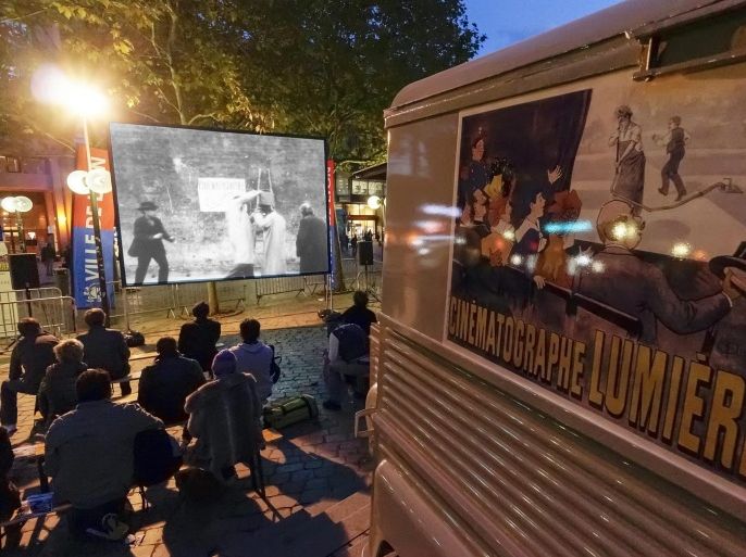 People watch a copy of a short film, one in a series of several of the first movies made in cinema history around 1895 by French brothers August and Louis Lumiere, in Lyon October 15, 2013. The street projections were part of the Lumiere 2013 Grand Lyon Film Festival which started on October 14 and is ongoing till October 20. REUTERS/Robert Pratta (FRANCE - Tags: ENTERTAINMENT)