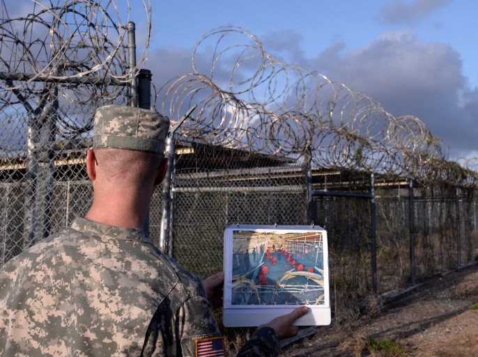 This photo made during an escorted visit and reviewed by the US military, shows a US Army officer showing a photograph of then operational and now abandoned 'Camp X-Ray' detention facility at the US Naval Station in Guantanamo Bay, Cuba, April 9, 2014. AFP PHOTO/MLADEN ANTONOV
