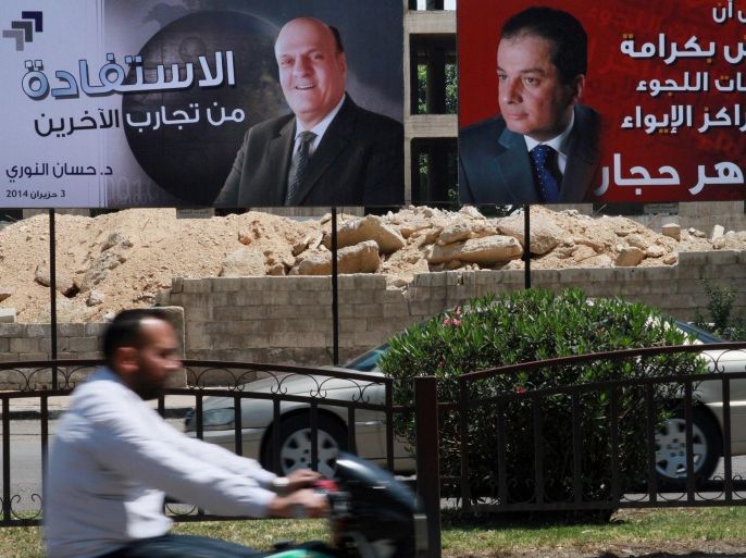 Syrian people drive by campaign posters of presidential candidates in Damascus, Syria, Monday, May 12, 2014. The Arabic, right, reads, "For us to live with dignity, neither in refugee camps nor in shelters, Maher Hajjar." The one at left reads, "There's a benefit in trying others, Hassan al-Nouri, June 4, 2014." On billboards and in posters taped to car windows, new portraits of President Bashar Assad filled the streets of Damascus on Sunday as Syria officially opened its presidential campaign despite a crippling civil war that has devastated the country and left large chunks of territory outside of government control. Assad faces two other candidates in the race: Hajjar and al-Nouri. (AP Photo)