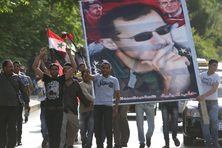 Syrian citizens who live in Lebanon shout slogans and carry a big portrait of Syrian President Bashar Assad, as they walk towards to the Syrian embassy to ballot their vote for their presidential elections, in Baabda, east of Beirut, Lebanon, Wednesday May 28, 2014. Thousands are flocking to the Syrian embassy in Lebanon as expat voting starts ahead of Syria's June 3 presidential election. (AP Photo/Hussein Malla)