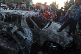 An Iraqi boy stands on a charred vehicle as people inspect the site of a car bomb explosion on May 15, 2014 in Baghdad's northern Shiite-majority district of Sadr City. An assault on a Baghdad court that included twin suicide bombings killed 10 people, the latest in a spate of explosions in Iraq's capital since an election last month