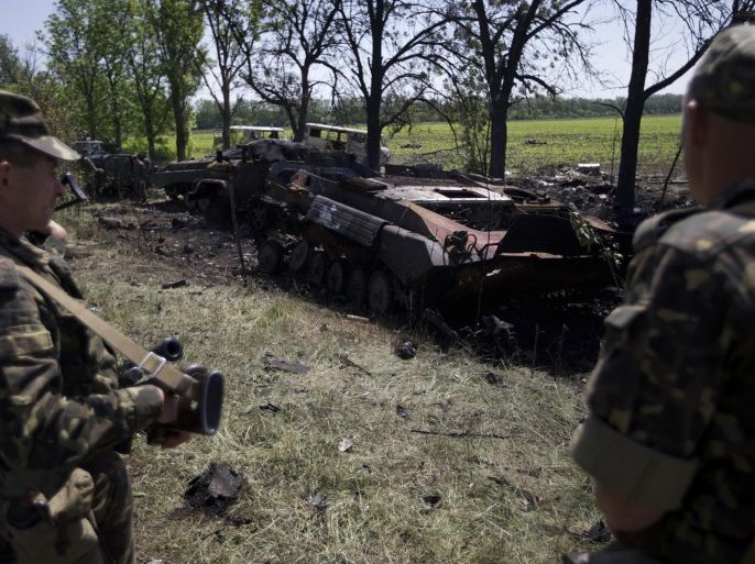 Ukrainian soldiers look at charred APCs at a gunfight site near the village of Blahodatne, eastern Ukraine, on Thursday, May 22, 2014. At least 11 Ukrainian troops were killed and about 30 others were wounded when Pro-Russians attacked a military checkpoint, the deadliest raid in the weeks of fighting in eastern Ukraine. Three charred Ukrainian armored infantry vehicles, their turrets blown away by powerful explosions, and several burned vehicles stood at the site of the combat. (AP Photo/Ivan Sekretarev)