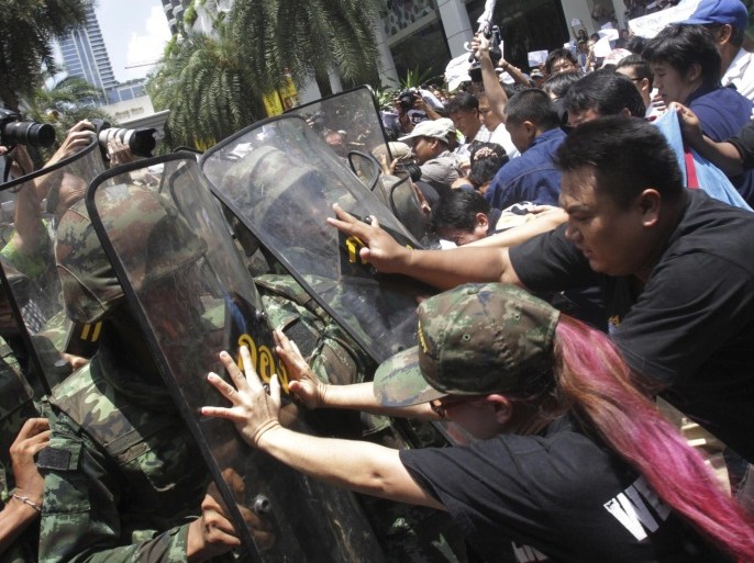 Protesters push Thai soldiers with riot shields during an anti-coup demonstration in Bangkok, Thailand, Sunday, May 25, 2014. Gen. Prayuth Chan-ocha in Thailand's ruling junta warned people Sunday not to join anti-coup street protests, saying normal democratic principles cannot be applied at the time, as troops fanned out in central Bangkok to prevent rallies. (AP Photo/Sakchai Lalit)