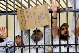 Supporters of the Muslim Brotherhood and other Islamists hold a cardboard sign with the "rabaa" symbol and from the defendants cage as they receive sentences ranging from death by hanging for one, life in prison for 13 and 8-15 years for the others after they were convicted of murder, rioting, and violence in a mass trial in Alexandria, Egypt, Monday, May 19, 2014. The four fingered gesture on the sign has become a symbol of the Rabaah al-Adawiya mosque, where supporters of ousted president Mohammed Morsi had held a sit-in for weeks that was violently dispersed in August, 2013. Mahmoud Hassan Ramadan Abdel-Nabi was sentenced to death for the killing a nine-year-old child by throwing him off the roof of a building during violent protests following the ouster of former Islamist President Mohammed Morsi last July. (AP Photo/Heba Khamis)