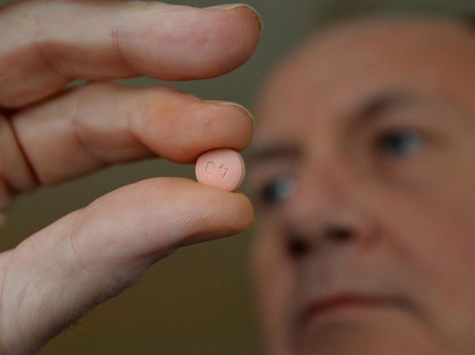 British man, Alwyn Daniel poses with a tablet of the anti-cholesterol drug Statins in London on March 21, 2014. As the home of cooked breakfasts and pints of beer, it is perhaps no surprise that Britain is the European king of anti-cholesterol drugs with some seven million users. But recommendations to widen the use of 'statins' -- the class of drugs used to battle cholesterol -- has sparked a national debate about their merits and whether they are really a silver bullet to stave off heart attacks.AFP PHOTO / BEN STANSALL