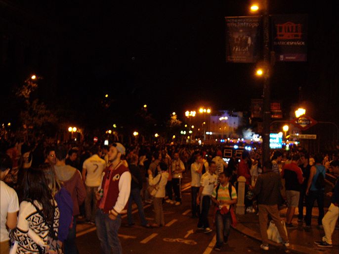 أنصار الريال يملأون الشارع بعد منتصف الليل وخلفهم الأضواء الزرقاء لسيارات قوات الشرطة التي تحمي الأمن العام في خلفية الصورة
