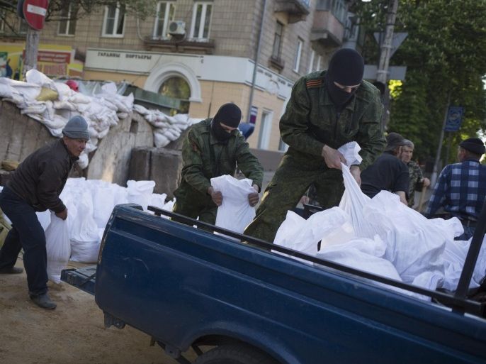 Masked pro-Russian activists strengthen the barricades in front of the Ukrainian regional office of the Security Service in Slovyansk, Ukraine, Wednesday, May 7, 2014. Russia has pulled back its troops from the Ukrainian border, Vladimir Putin told diplomats Wednesday as he urged insurgents in southeastern Ukraine to postpone their planned referendum Sunday on autonomy. (AP Photo/Alexander Zemlianichenko)