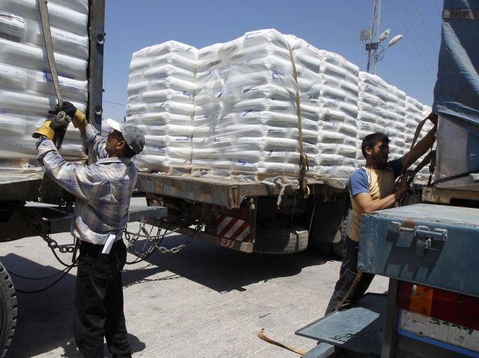 Palestinian workers remove the straps from trucks loaded with goods that arrived in Rafah town through the Kerem Shalom commercial crossing between Israel and the southern Gaza Strip on April 27, 2014 as the crossing reopened after the Jewish Passover holidays. The coastal strip, whose air and sea lanes are blocked by Israel, has three land crossings; Erez and Kerem Shalom with Israel and Rafah with Egypt. AFP PHOTO / SAID KHATIB