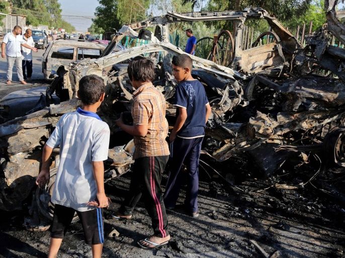 Iraqi boys look inside of a destroyed vehicle the day after a car bomb attack near an outdoor market in Baghdad's Shiite neighborhood of Sadr City, Iraq, Friday, May 16, 2014. Bombings and shootings around Iraq's capital, including an attack involving militants using a fake checkpoint to kill army officers, killed and wounded dozens of people on Thursday, officials said. (AP Photo/Karim Kadim)