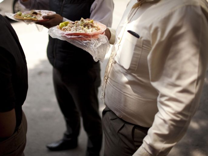 FILE - In this July 10, 2013, file photo, office workers eats tacos at an outdoor food stand during lunch time in Mexico City. Mexico has surpassed the United States in levels of adult obesity. Mexico's new food labeling rules were supposed to help fight an obesity epidemic, but activists and experts said Monday, april 21, 2014, that they may actually encourage the public to consume high levels of sugar. (AP Photo/Ivan Pierre Aguirre,File)