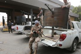 Former rebel fighters who are now intergrated into the Libyan army and form the Diraa al-Gharbiya brigade, are seen with their weapons guarding the western entrance of the capital Tripoli on May 19, 2014. A dramatic spike in lawlessness in Libya's two largest cities has edged the country closer to civil war between heavily armed rival militias, stirring concern abroad and on oil markets. AFP PHOTO/MAHMUD TURKIA