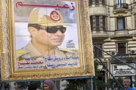 Egyptian walk past a huge poster of Egypt's former Defence Minister and armed forces chief General Abdul Fatah Al-Sisi in downtown Cairo, on March 27, 2014. Sisi is assured of winning Egypt's forthcoming presidential vote but at the cost of reviving the era of strongman rule as he faces a dilapidated economy and rising militancy. AFP PHOTO / KHALED DESOUKI