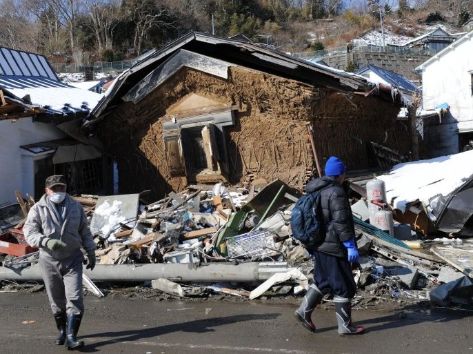 Rescuers walk past a house made of mud standing between to other damaged houses in the wreckage of Miyako near the port, in Iwate prefecture on March 17, 2011 after the devastating March 11 quake and tsunami. Japan faces the threat of major power blackouts unless electricity use is reduced, a government minister said March 17 in the aftermath of a massive earthquake and tsunami.