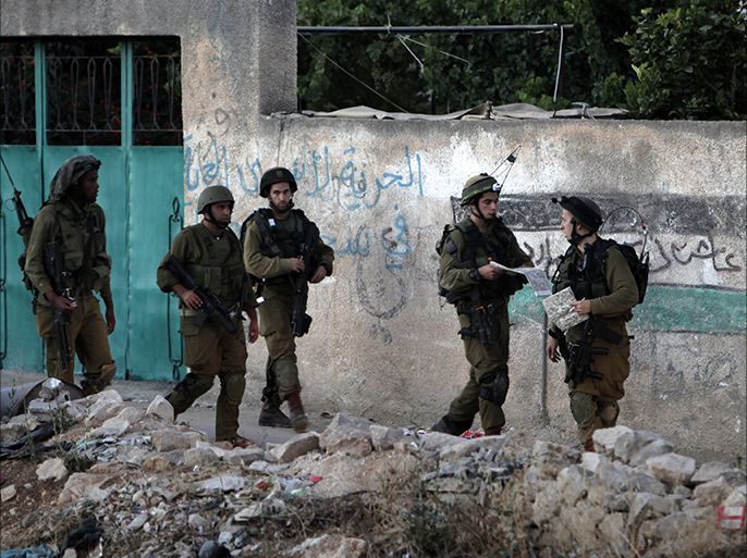 Israeli soldiers take part in a search operation in the West Bank village of Awarta on June 26, 2014, as part of the operation to locate the three teenagers the army believes were abducted by Islamist movement Hamas on June 12. Israeli Israeli Prime Minister Benjamin Netanyahu praised Palestinian president Mahmud Abbas for condemning the alleged kidnapping of three teenagers by Hamas, but criticised his unity pact with the Islamist movement. Netanyahu spoke as Israel began to wind down a huge crackdown on Hamas, having arrested hundreds in an operation to find the youngsters who went missing in the southern West Bank nearly two weeks ago. AFP PHOTO/JAAFAR ASHTIYEH