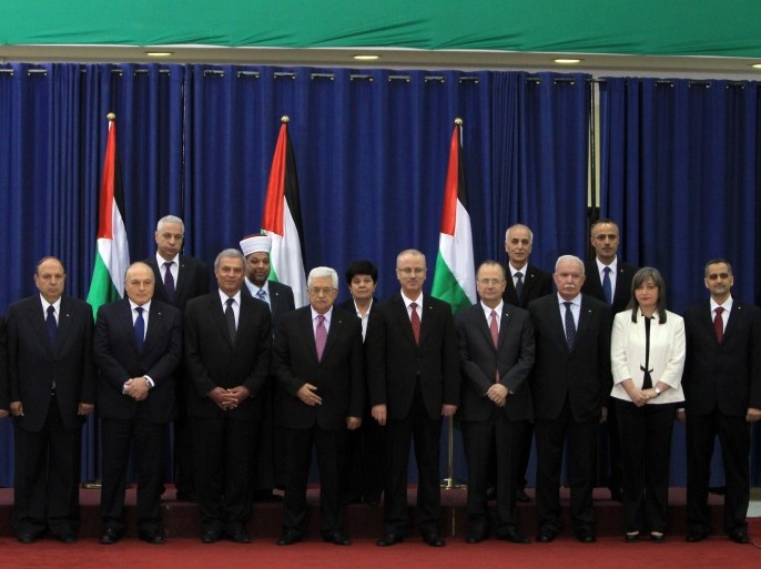 Palestinian president Mahmud Abbas (C) poses for a picture with the members of the new Palestinian unity government in the West Bank city of Ramallah June 2, 2014. Abbas hailed the 'end' of Palestinian division as a new government took its oath under a unity deal between leaders in the West Bank and Gaza. AFP PHOTO/ABBAS MOMANI