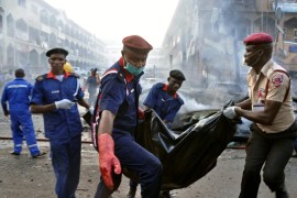 AP10ThingsToSee - Rescue workers carry the remains of a person in a body bag after an explosion at a shopping mall in Abuja, Nigeria, Wednesday, June 25, 2014. Police said more than 20 people were killed and many wounded in the explosion. (AP Photo/Olamikan Gbemiga)