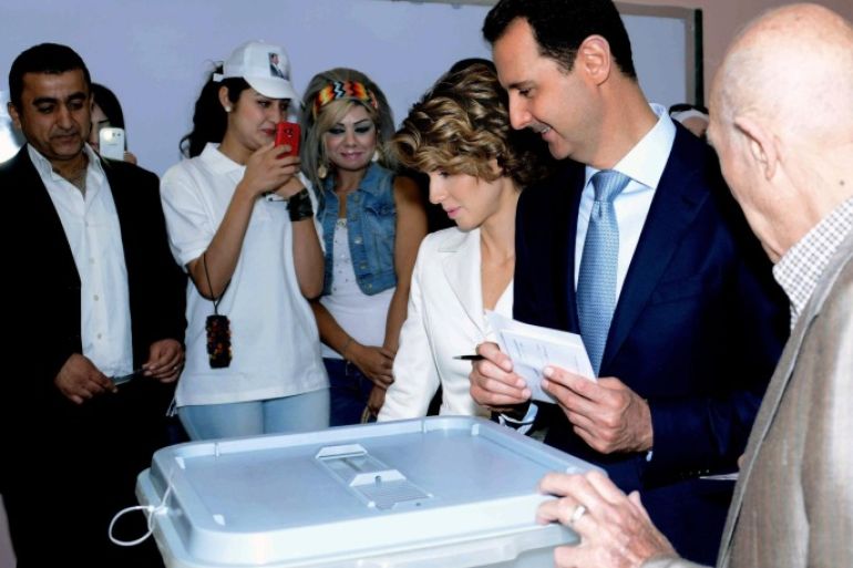 In this photo released by the Syrian official news agency SANA, Syrian President Bashar Assad, second right, casts his vote as Syrian first lady Asma Assad, stands next to him at a polling station, in Damascus, Syria, Tuesday, June 3, 2014. Thousands of Syrians lined up outside polling centers in government-controlled areas around the country to vote Tuesday in the presidential election that Assad is widely expected to win but which has been denounced by critics as a sham. (AP Photo/SANA)