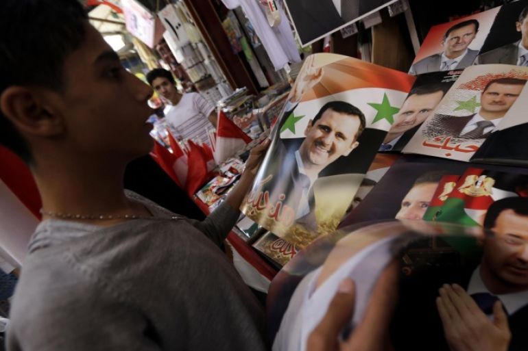 A Syrian man looks at campaign posters of Syrian President Bashar al-Assad displayed on a stall at a market in the capital Damascus on June 1, 2014. Syria began its last day of campaigning for the June 3 presidential elections expected to return incumbent Bashar al-Assad to power, a vote the opposition has labelled a 'parody of democracy'. AFP PHOTO/JOSEPH EID