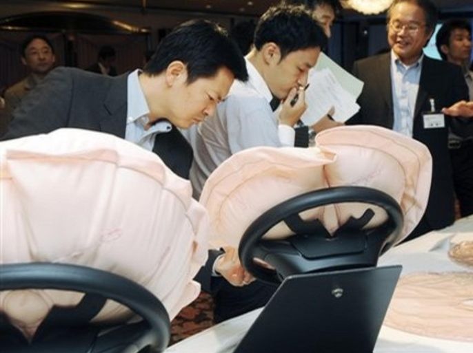 Reporters take a close look at Honda Motor Co.'s newly-developed air bags on display in Tokyo Thursday, Sept. 18, 2008. The new air bags is the world's first that inflates in stages, mitigating the force of its deployment, Honda says. They inflate quicker but gentler for drivers, offering protection in crashes while reducing their possible bruising impact.