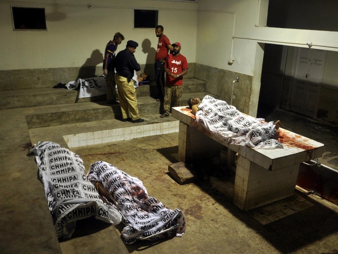 رجال أمن باكستانيون يعاينون جثث بعض القتلى في الهجوم على المطار (الأوروبية)