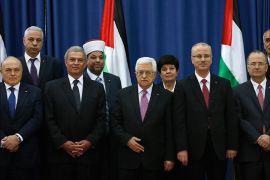 Palestinian Prime Minister Rami Hamdallah (4th L) and Palestinian President Mahmoud Abbas (3rd L) pose for a group photo with Palestinian ministers during a swearing-in ceremony of the unity government, in the West Bank city of Ramallah June 2, 2014. Abbas swore in a unity government on Monday after overcoming a last-minute dispute with the Hamas Islamist group. REUTERS/Mohamad Torokman (WEST BANK - Tags: POLITICS)
