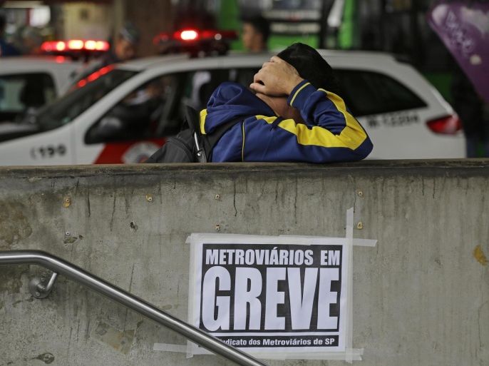 A commuter stands at the entrance of the Ana Rosa metro station where a sign hangs that reads in Portuguese "Subway workers on strike" on the second day of a metro strike in Sao Paulo, Brazil, Friday, June 6, 2014. Overland commuter train operators went on strike Thursday, stranding the millions of people who use Sao Paulo's public transport systems. (AP Photo/Nelson Antoine)
