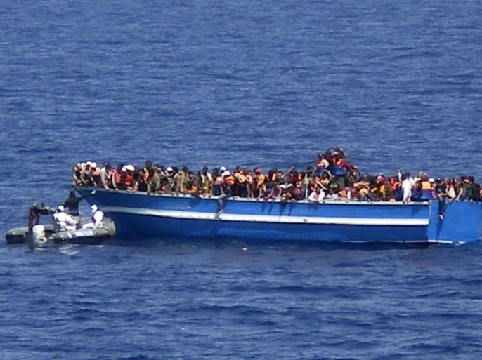 In this photo released by the Italian Navy on Monday, June 30, 2014, and taken on Sunday, June 29, 2014, a motorboat of the Italian Navy approaches a boat of migrants in the Mediterranean Sea. The bodies of some 30 would-be migrants were found in in the hold of a packed smugglers' boat making its way to Italy, the Italian navy said Monday. The boat was carrying nearly 600 people, and the remaining 566 survivors were rescued by the navy frigate Grecale and were headed to the port at Pozzallo, on the southern tip of Sicily. (AP Photo/Italian Navy, ho)