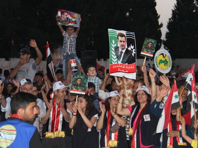 In this Saturday, May 31, 2014, photo released by the Syrian official news agency SANA, supporters of Syrian President Bashar Assad hold his portraits and wave Syrian flags during a demonstration in support of his candidacy for presidential election in the costal city of Tartous, Syria. It is Syria’s first multi-candidate presidential election in nearly half a century. But the vote on Tuesday, June 3, still has the feel of a referendum and is being touted by Assad’s government as a measuring scale for Syrians’ support of his three-year brutal military crackdown on dissent. (AP Photo/SANA)