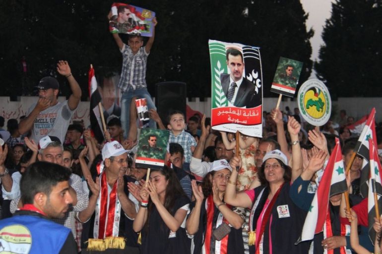 In this Saturday, May 31, 2014, photo released by the Syrian official news agency SANA, supporters of Syrian President Bashar Assad hold his portraits and wave Syrian flags during a demonstration in support of his candidacy for presidential election in the costal city of Tartous, Syria. It is Syria’s first multi-candidate presidential election in nearly half a century. But the vote on Tuesday, June 3, still has the feel of a referendum and is being touted by Assad’s government as a measuring scale for Syrians’ support of his three-year brutal military crackdown on dissent. (AP Photo/SANA)