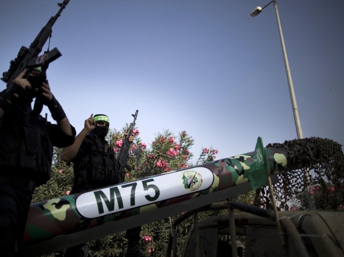 Palestinian militants of the Ezzedine al-Qassam Brigades, Hamas's armed wing, flank a model of a Gaza Strip made M75 rocket during an anti-Israel parade as part of the celebrations marking the first anniversary of an Israeli army operation launched after the killing of top Hamas military commander Ahmed Jaabari, on November 13, 2013 in Gaza City. A year after trading fire in a week-long war in Gaza, in which more than 170 Palestinians and six Israelis were killed, Israel and Hamas are squaring up for another confrontation, despite both sides appearing reluctant to make the first move . AFP PHOTO / MAHMUD HAMS