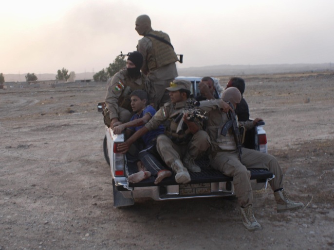 ‪(رويترز)‬ عناصر من البشمركة الكردية ينقلون جرحى بعد مواجهات مع تنظيم الدولة الإسلامية 