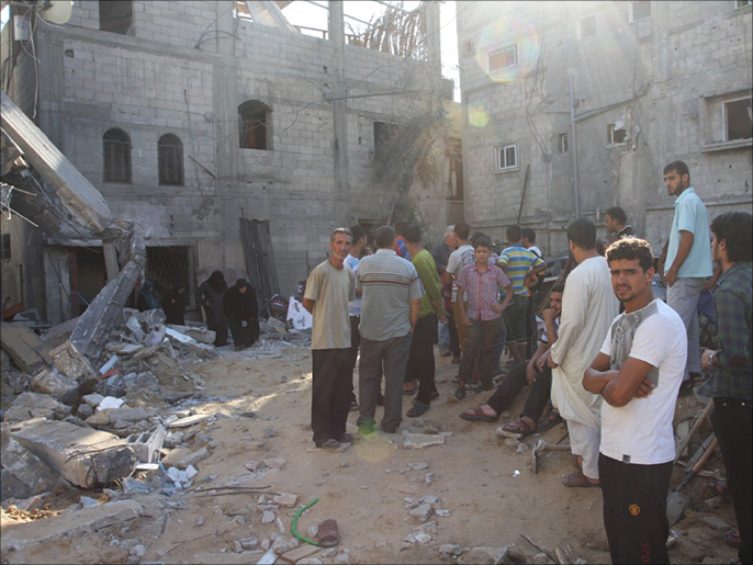 ‪فلسطينيون يعاينون آثار الدمار الناجم عن القصف‬ (الجزيرة)