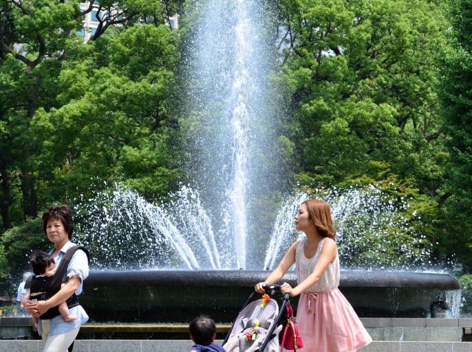 Mothers with their children walk past a water fountain at a park in Tokyo on July 29, 2014. Sweltering summer heat in Japan has left at least 15 people dead over the past week, while more than 8,000 others were rushed to hospital with heatstroke symptoms, official figures showed on July 29. AFP PHOTO / Yoshikazu TSUNO