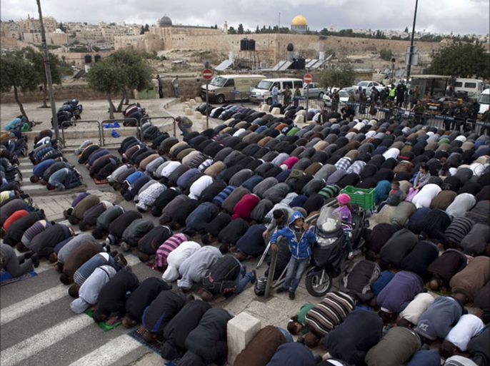 Israeli border policemen stand guard as a Palestinian Muslims perform Friday prayers on a street in the Arab east Jerusalem neighborhood of Ras-Al Amud with the al-Aqsa mosque in the background, on April 5, 2013