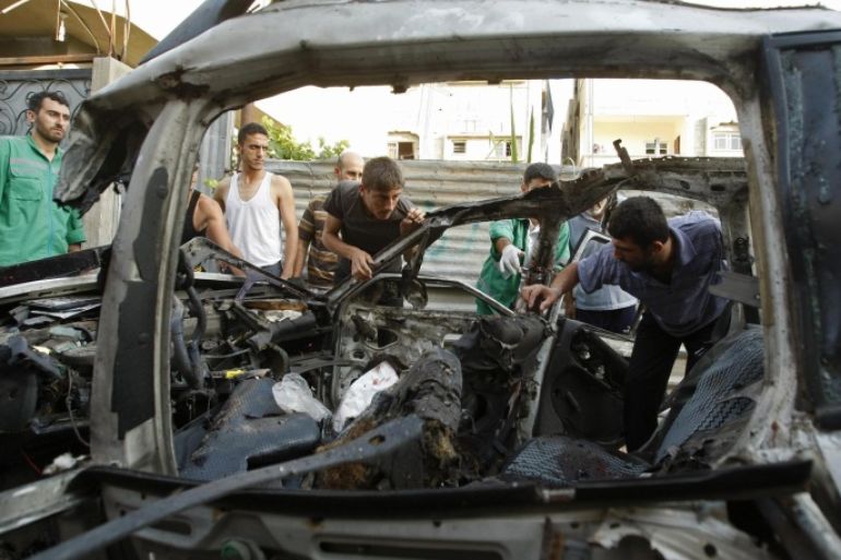 Palestinians inspect the remains of a car which the police said was targeted in an Israeli air strike, in Gaza City July 10, 2014. Israel pressed on with a punishing aerial offensive in Gaza for a third day on Thursday, killing eight members of a family including five children in a predawn strike, Palestinian officials said, while militants fired rockets at Israeli cities. REUTERS/Ahmed Zakot (GAZA - Tags: POLITICS CIVIL UNREST)