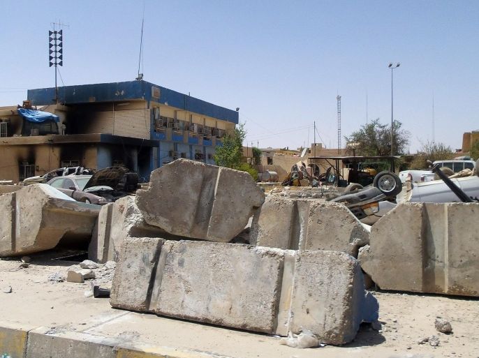 This photo taken on Tuesday, July 1, 2014, shows destroyed vehicles in front of a burned police station after clashes between fighters of the al-Qaida-inspired Islamic State of Iraq and the Levant and Iraqi security forces in central Tikrit, 80 miles (130 kilometers) north of Baghdad, Iraq. The Islamic State of Iraq and the Levant announced this week that it has unilaterally established a caliphate in the areas under its control. It declared the group's leader, Abu Bakr al-Baghdadi, the head of its new self-styled state governed by Shariah law and demanded that all Muslims pledge allegiance to him. (AP Photo)