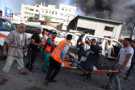 Palestinians carry the body of a local Palestinian journalist, whom medics said was killed by Israeli shelling near a market in Shejaia, as smoke rises in the east of Gaza City July 30, 2014. Israeli strikes near a market in the eastern Gaza Strip killed 15 Palestinians on Wednesday, the local health ministry said. Residents said that Israeli shelling and two missiles from the air hit the area in Shejaia, on the fringes of the city of Gaza. Ashraf al-Qidra, spokesman of the Gaza Health Ministry, said 160 people were also wounded. An Israeli military spokeswoman said she was checking the report. Israel launched its offensive in response to rocket salvoes fired by Gaza's dominant Hamas Islamists and their allies. REUTERS/Ashraf Amrah (GAZA - Tags: POLITICS CIVIL UNREST MEDIA) TEMPLATE OUT