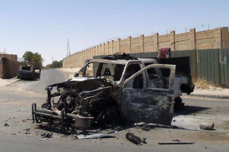 This photo taken on Tuesday, July 1, 2014, shows destroyed police trucks after clashes between fighters of the al-Qaida-inspired Islamic State of Iraq and the Levant and Iraqi security forces in central Tikrit, 80 miles (130 kilometers) north of Baghdad, Iraq. The Islamic State of Iraq and the Levant announced this week that it has unilaterally established a caliphate in the areas under its control. It declared the group's leader, Abu Bakr al-Baghdadi, the head of its new self-styled state governed by Shariah law and demanded that all Muslims pledge allegiance to him. (AP Photo)