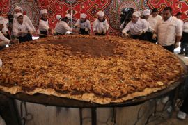 Palestinian chefs give the final touches to a huge serve of Musakhan, a traditional Palestinian dish made of chicken, flat bread, nuts and spices, on April 19, 2010 in the West Bank village of Arura, near Ramallah. Palestinian prime minister Salam Fayyad attended the event.