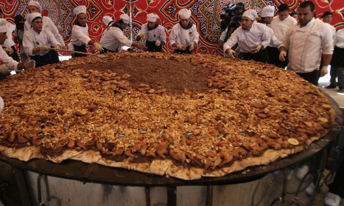 Palestinian chefs give the final touches to a huge serve of Musakhan, a traditional Palestinian dish made of chicken, flat bread, nuts and spices, on April 19, 2010 in the West Bank village of Arura, near Ramallah. Palestinian prime minister Salam Fayyad attended the event.
