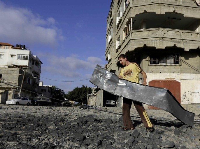 A Palestinian man carries rubble near a Hamas training camp following an Israeli air strike on it early morning in Gaza City Thursday, July 3, 2014. Israeli military carried out airstrikes on the Gaza Strip after Palestinian militants fired rockets into Israel early Thursday. The Israeli military said the air force struck 15 "terror sites" in Gaza. "The targets included weapons manufacturing sites as well as training facilities," a military spokesman said. (AP Photo/Adel Hana)